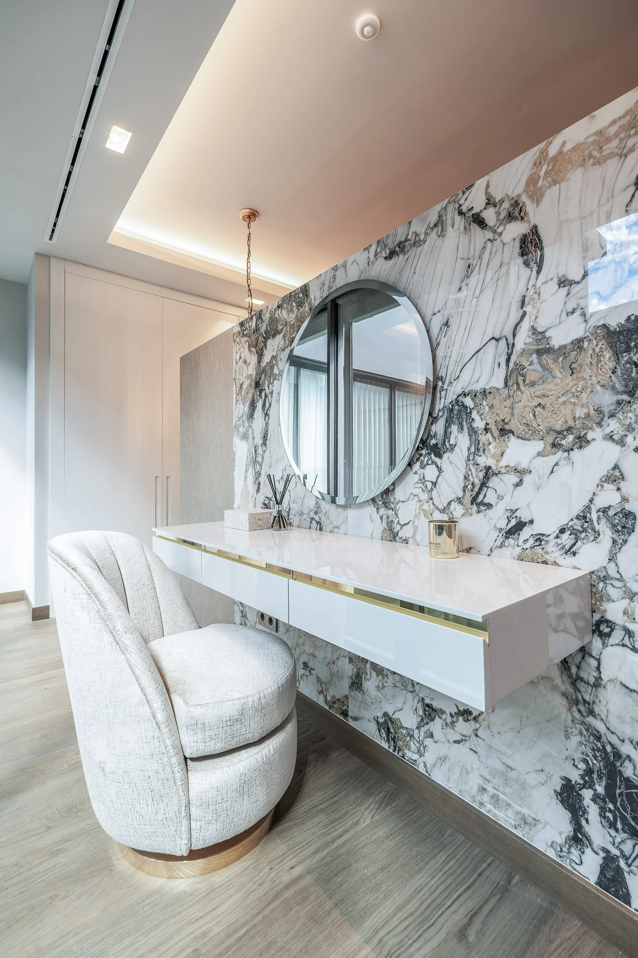 Stone vanity and upholstered stool in the dressing area