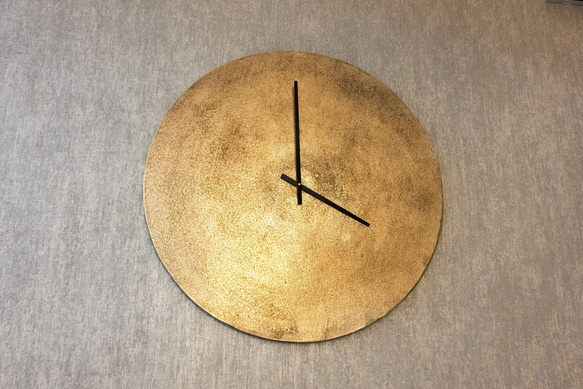 Round gold-toned wall clock on a textured wall