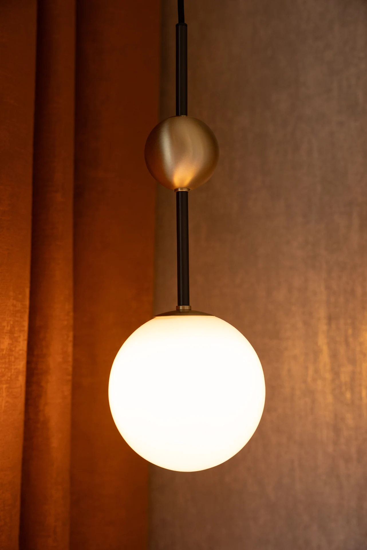 Bedside globe pendant against timber panelling