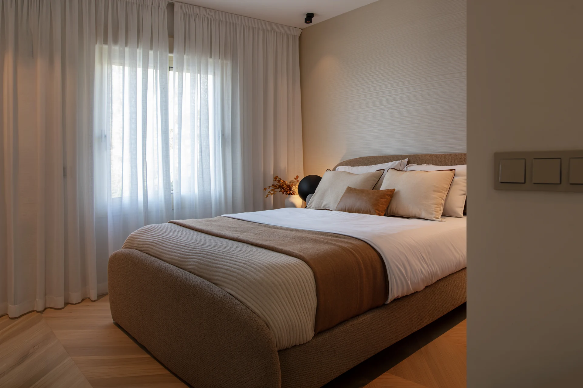 Bedroom with neutral bedding and full-height curtains
