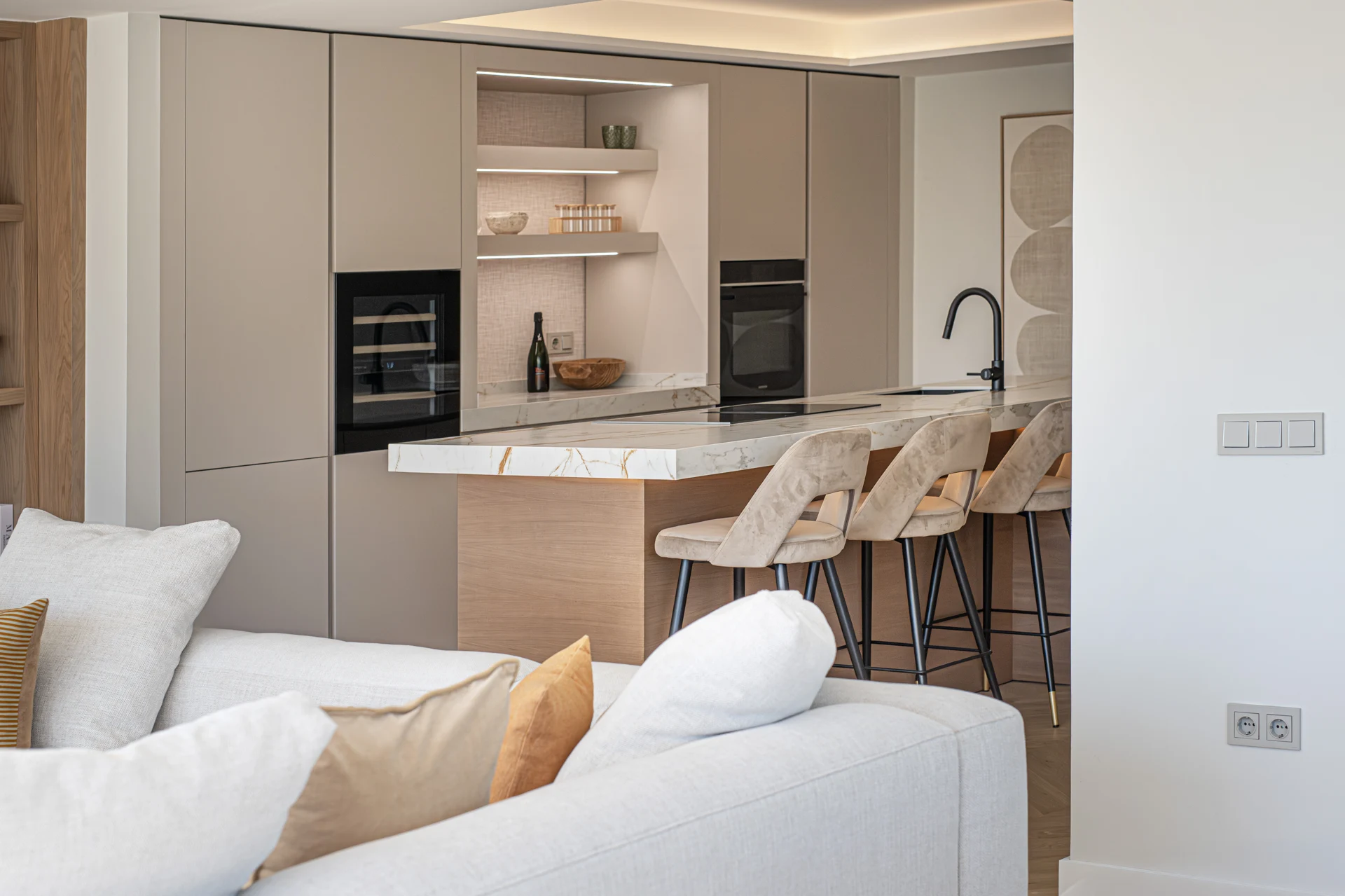 Open-plan kitchen with pale cabinetry and upholstered island stools