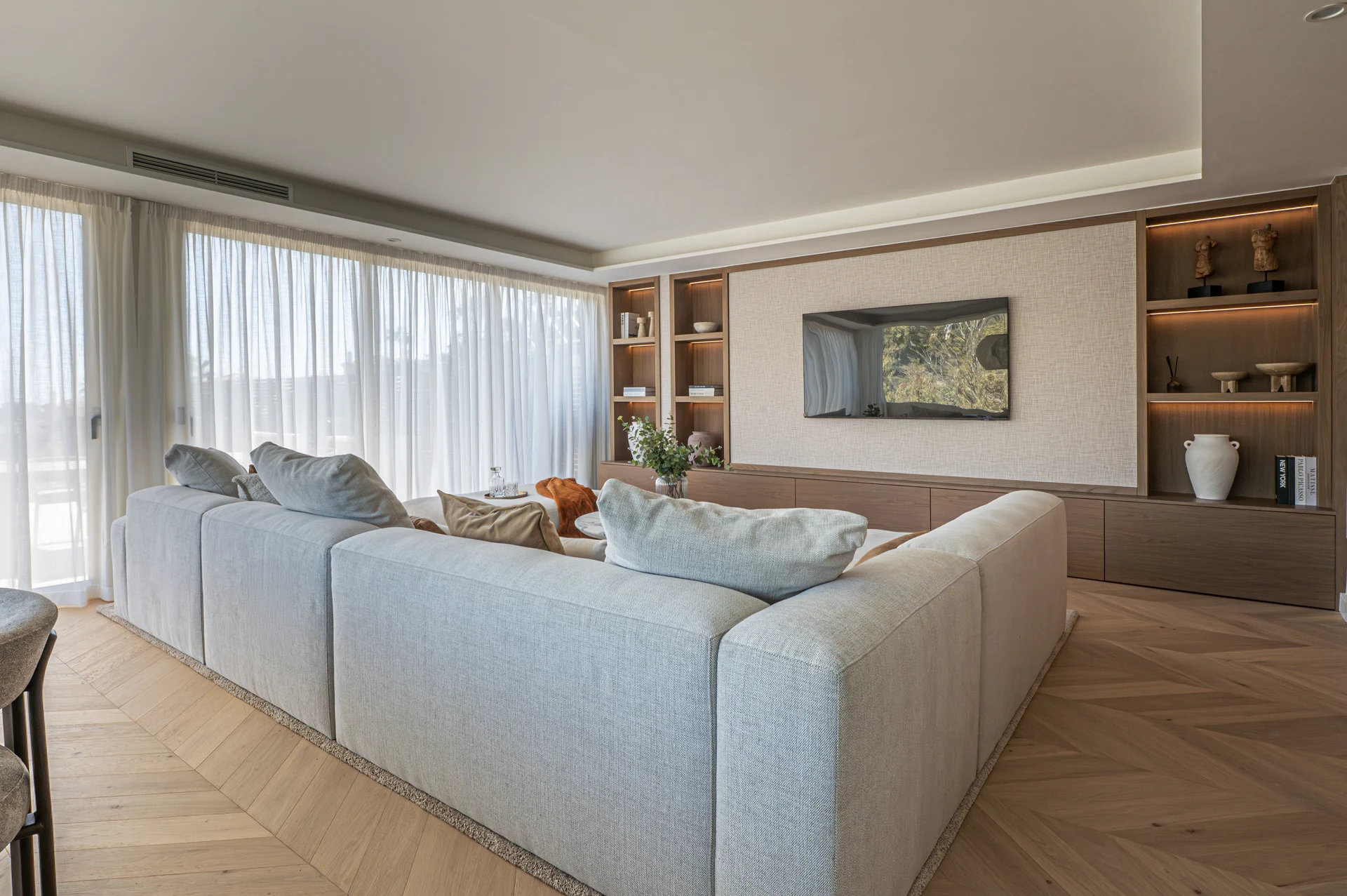 Pale sectional sofa and fitted timber shelving in the living room