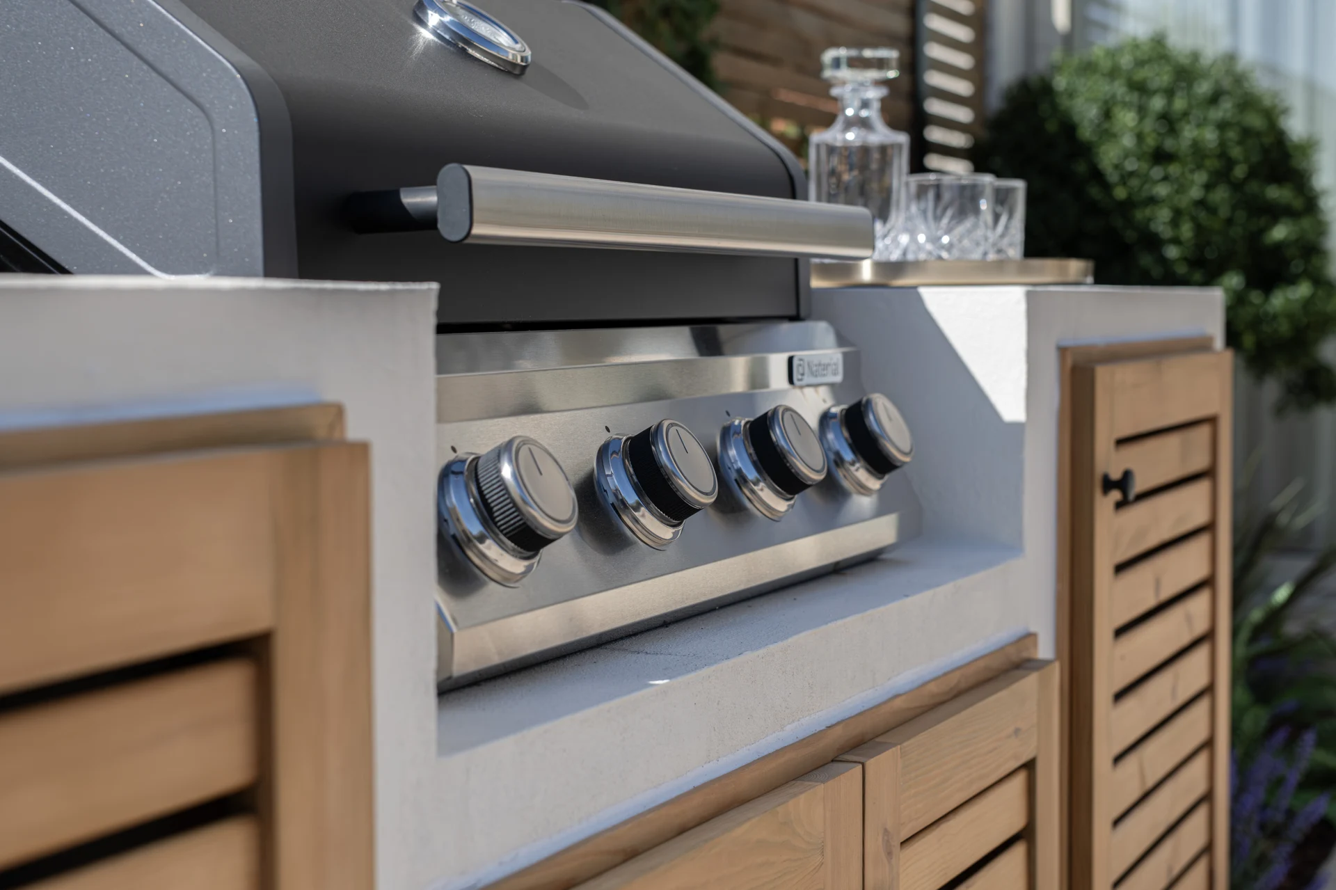 Built-in barbecue with pale masonry and timber-fronted outdoor cabinets