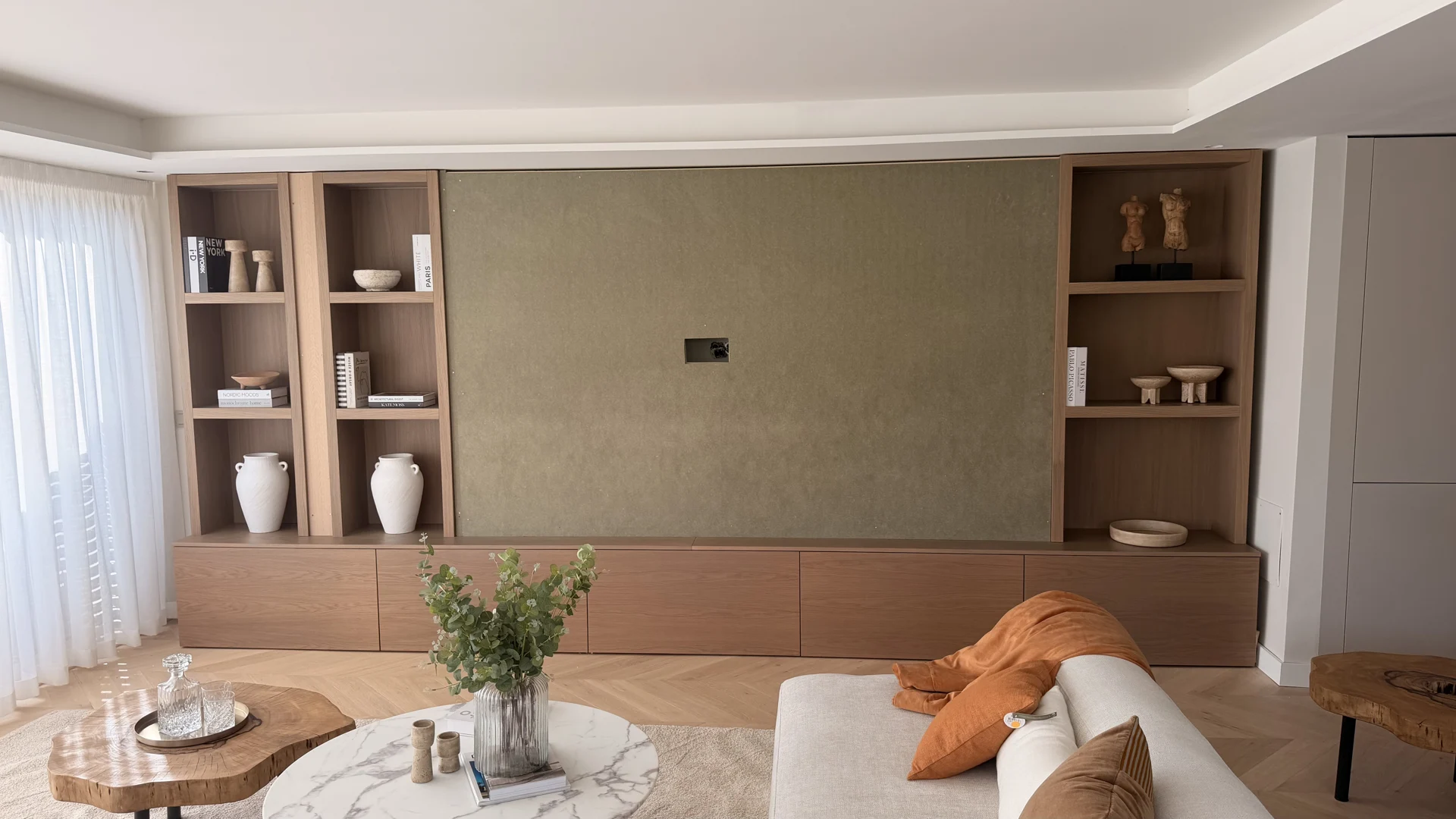 Furnished living room with timber shelving, textured wall and layered seating