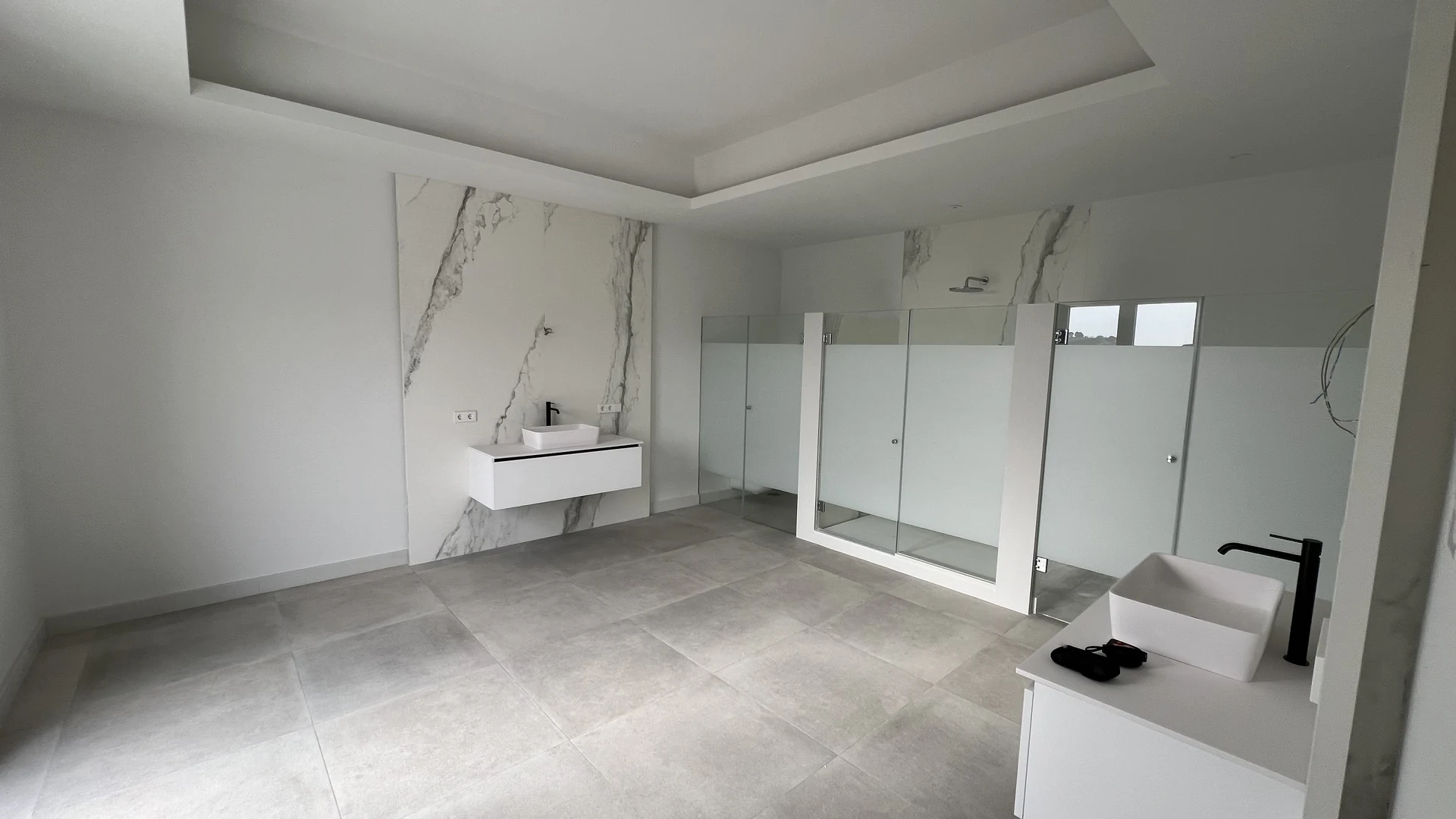 Bathroom before redesign, with white vanity units and a glazed shower enclosure