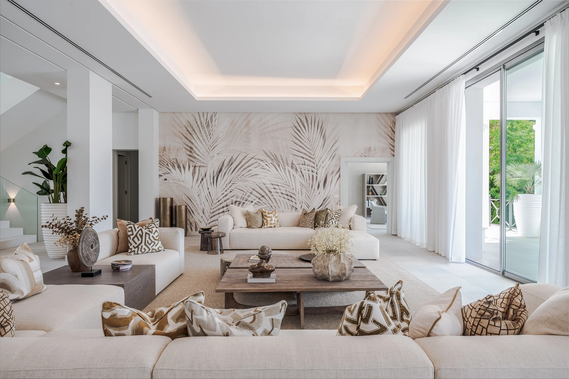 Completed living room with kentia-leaf wallcovering, upholstered seating, rugs and decorative styling