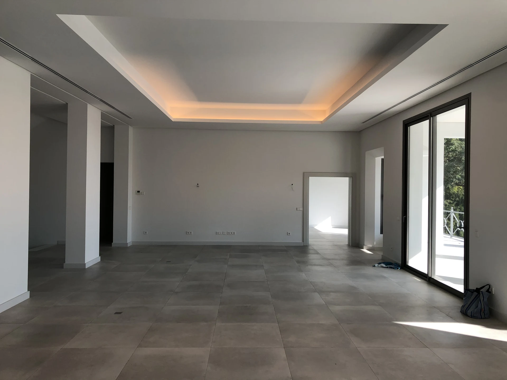 Living room before furnishing, with a plain rear wall and empty tiled floor