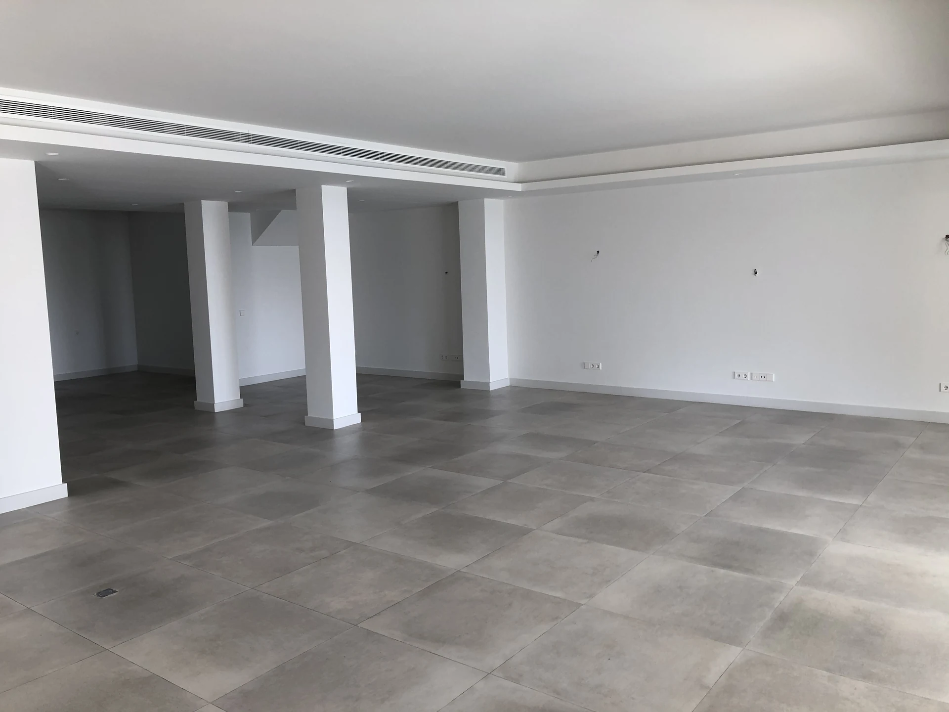 Unfurnished interior with structural columns and an empty tiled floor