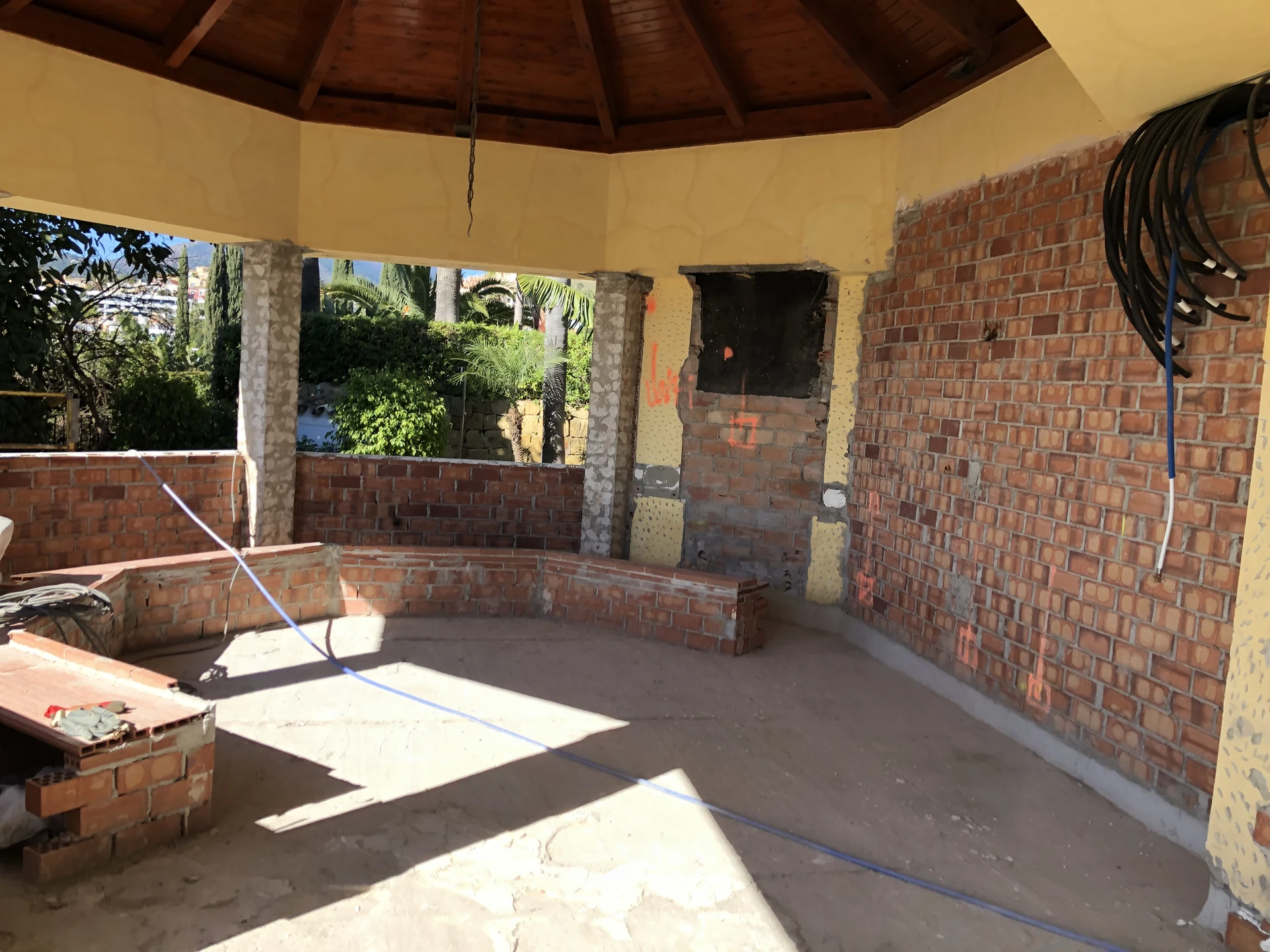 Existing garden pavilion during works, with exposed brickwork and a timber roof